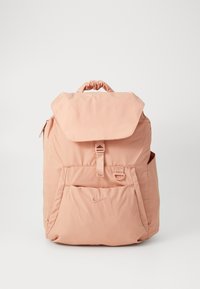 Roze nylon rugzak met een getrokken bovenkant, platte klep, voorvak en zijnetvak. Heeft een klein logo op de voorkant. Eenvoudige textuur.