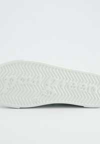 White rubber shoe sole featuring herringbone pattern and embossed "paul green" logo for grip and branding on the underside.