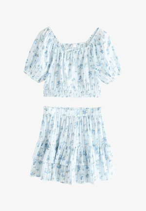 Svetlomodrý kvetinový crop top s nafúknutými rukávmi a zodpovedajúca vrstvená mini sukňa s malými žltými a modrými kvetinovými vzormi.