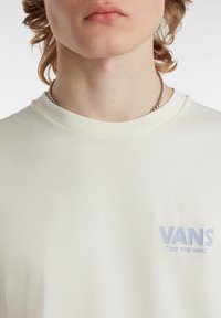 Crewneck-T-Shirt aus off-white Baumwolle, mit hellblauem "VANS"-Logo und dem aufgestickten Text "OFF THE WALL" auf der linken Brust.