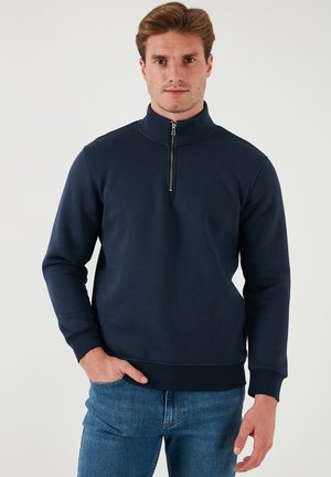 Marineblauer Sweatshirt mit hohem Kragen und halbem Reißverschluss. Hergestellt aus weichem Stoff, mit gerippten Bündchen und Saum für eine bequeme Passform.
