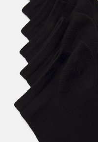 Schwarze Socken aus strukturiertem Stoff mit einem gerippten Design und glatter Oberfläche, in einem gestapelten Format angeordnet.