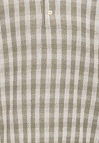 Tissu texturé avec des rayures verticales blanches et marron clair et un petit bouton beige près du centre supérieur.