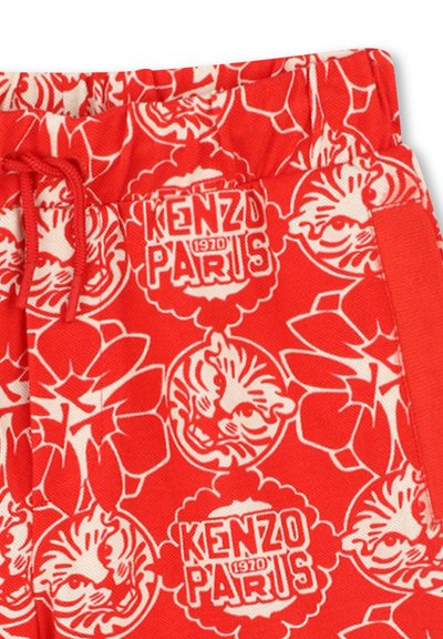 Shorts en coton rouges avec un imprimé floral blanc et un tigre, taille élastique avec cordon de serrage, et texte logo "KENZO PARIS (1970)" sur le côté.