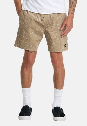 Beige floral swim shorts with an elastic waistband, drawstring closure, and side pockets. Accented with a black brand logo patch.
