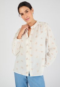 Camicia bianca con motivo paisley marrone chiaro, colletto arruffato e maniche lunghe, realizzata in un tessuto leggero e traspirante.