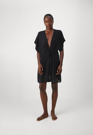 Zwarte chiffon jurk met een diepe V-hals, korte mouwen en een strik taille. Heeft geschulpte randen en een vloeiende silhouet.