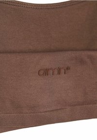 Bruine stof met een zachte textuur, met een zichtbaar logo "amn" dat in het materiaal is geperst, wat een naadloos ontwerp en schone randen benadrukt.