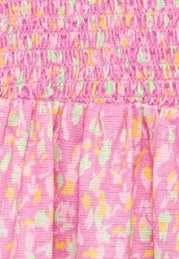 Růžová tkanina s nahrnutým stehem a abstraktním květinovým vzorem v zelené, žluté a oranžové barvě na texturovaném tkaném materiálu.