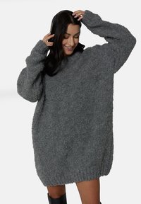 Przesadny szary sweter wykonany z miękkiej, teksturowanej tkaniny, z długimi rękawami i żebrowanym dołem, charakteryzujący się luźnym, grubym krojem.