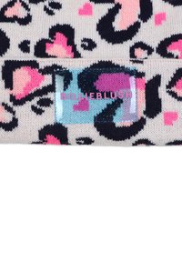 Bonnet en tricot avec une base crème, des taches de léopard noires et des cœurs roses. Comprend une étiquette bleue brillante avec le logo "BILLIEBLUSH".