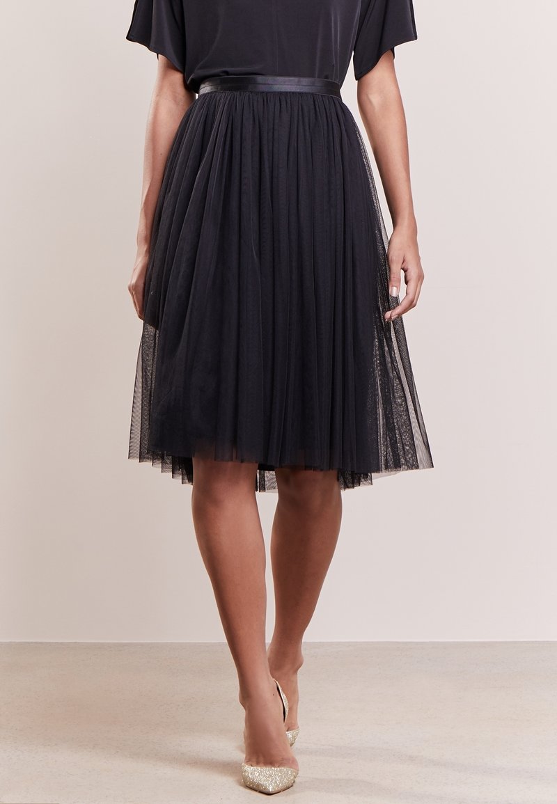 Gonna nera in tulle con un design plissettato, dotata di una vita liscia e aderente. L'orlo è leggermente trasparente, sovrapposto a una gonna solida.