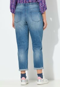 Vaaleansiniset rentot malliset farkut, joissa on käännetty lahje ja kaksi takataskua. Yhdistetty valkoisiin tennareihin ja kuvioituihin sukkiin.