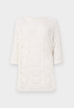 Top alb tricotat, cu un model geometric de broderie deschisă, decolteu rotund și mâneci scurte. Fabrică ușoară și texturată.