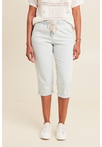 Lichtblauwe, cropped joggerbroeken met een elastische tailleband en verstelbaar trekkoord, met opgerolde boorden. Gecombineerd met witte sneakers.