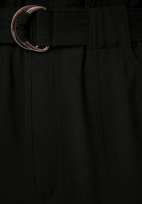 Černé látkové kalhoty se širokým pasem a stříbrnou kulatou sponou. Obsahují vertikální sklady a boční kapsy.