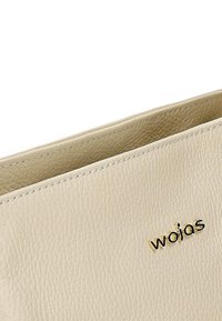 Borsa a tracolla in pelle crema con finitura testurizzata, caratterizzata da un logo in rilievo dorato. I bordi sono cuciti per una maggiore durata.