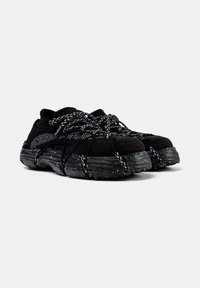 Black athletic shoes with thick textured soles and black-and-white speckled laces wrapped around for a secure fit.