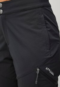 Sorte udendørs shorts i en glat tekstur, med en lynlåslomme i siden og metalknaplukninger i taljen.
