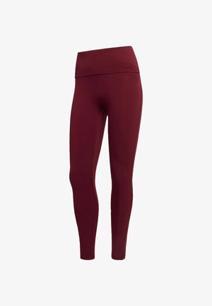 Legging bordeaux en tissu extensible avec une taille haute et large et un design sans coutures, présentant une texture lisse et une silhouette ajustée.