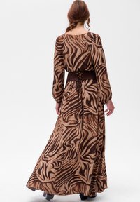 Maxi sukienka z przezroczystego brązowego materiału z wzorem w zebrę, z długimi rękawami i dopasowanym brązowym pasem w talii z detalami w postaci sznurowania z tyłu.