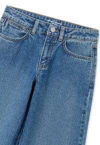 Jeans de denim azul con bolsillos frontales, trabillas, botón de metal, cierre de cremallera y textura desgastada cerca de la cintura y los muslos.
