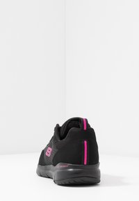 Scarpa sportiva nera con tomaia in rete, dettagli in rosa a contrasto e suola testurizzata. Presenta un tacco imbottito per un maggiore supporto.