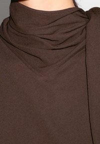 Brun stof turtleneck med et draperet design, der har en blød tekstur og en smal, V-formet udskæring. Ingen synlig hardware eller mønstre.