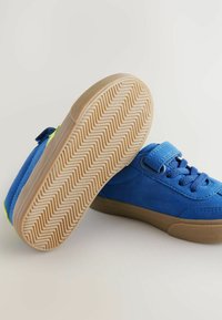 Blauwe suède lage sneakers met een gestructureerde rubberen zool, voorzien van een klittenbandsluiting, een ronde neus en een zigzagpatroon op de zool.