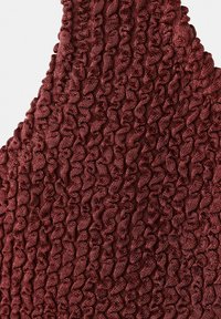 Makro záber na bordovú látku s hustou vertikálne zvlnenou štruktúrou a pleteným vzorom.