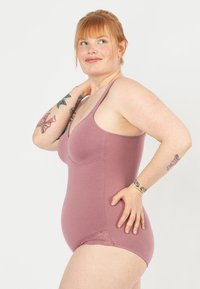 Drahtloser Body in Mauve, aus weichem Stoff mit glatter Textur. Mit Spitzenrand an den Beinöffnungen und verstellbaren Trägern.