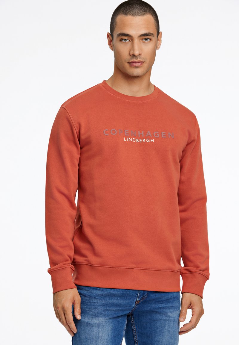 Felpa color ruggine con colletto tondo e maniche lunghe, con il testo "COPENAGHEN LINDBERGH" in grigio su petto.