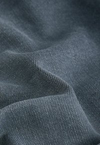 Tissu en coton de couleur gris foncé, présentant une surface lisse et légèrement texturée avec un subtil motif de tissage diagonal.