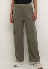 Pantalons cargo vert olive avec une taille élastique, des poches latérales et deux grandes poches à rabat. Fabriqués en tissu léger, ils offrent une coupe ample.