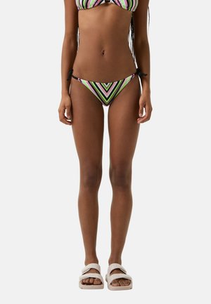 Gestreiftes Bikini mit Schwarz-, Grün-, Pink- und Weißtönen; verfügt über einen Bindeband-Bikiniunterteil und ein Dreieck-Oberteil. Trägt dazu weiße Rutschsandalen.
