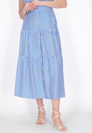 Niebiesko-biała midi spódnica w pionowe paski z guzikami z przodu, noszona z cielistymi sandałami na blokowym obcasie z paskami.