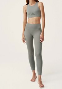 Ljusgrön athleisure-set som består av en sömlös sport-bh med en triangel-meshaccent och högmidjade leggings, båda i ett mjukt tyg.
