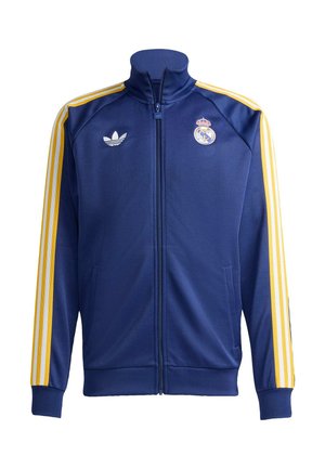 Μπλε ναυτικό τζάκετ Adidas με τρεις κίτρινες ρίγες στα μανίκια, ολόκληρο φερμουάρ και λογότυπο της Ρεάλ Μαδρίτης στο στήθος.