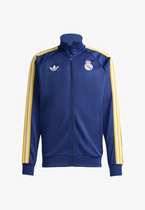 Marineblauw Adidas trainingsjack met gele drie strepen op de mouwen, een volledige ritssluiting en het Real Madrid-logo op de borst.