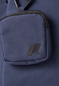Sacchetto di stoffa blu navy con una cerniera nera e un logo nero. Presenta una superficie testurizzata e un attacco per moschettone.