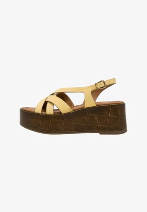 Gele suède platform sandalen met gekruiste bandjes, een bruine, getextureerde sleehakzool en een verstelbare enkelband voor een stevige pasvorm.