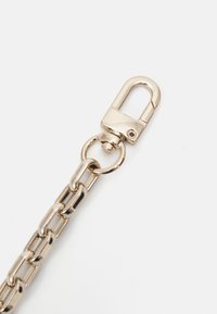 Srebrny łańcuch metalowy z dużymi ogniwami. Wyposażony w zapięcie typu lobster i okrągły pierścień do mocowania. Gładka, błyszcząca tekstura o wypolerowanej powierzchni.