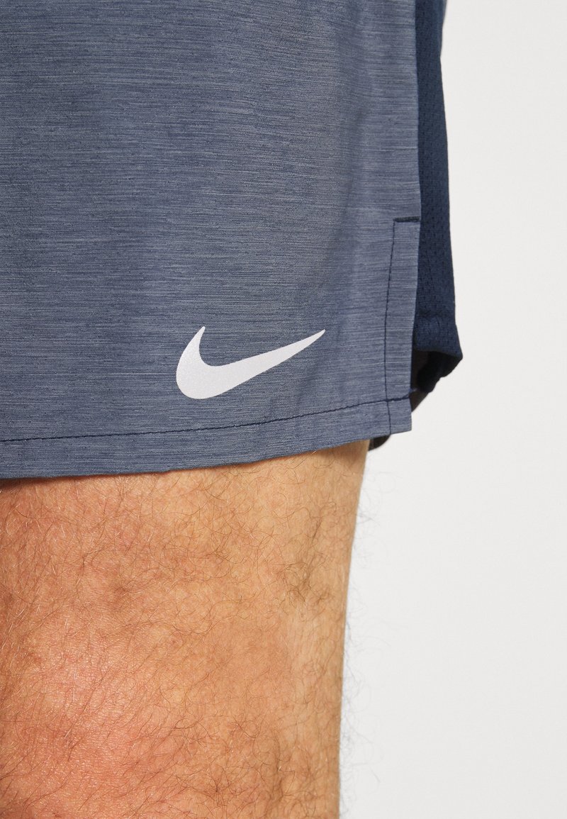 Marinblå Nike-shorts gjorda av texturerat, lättviktsmaterial. Har en vit logotyp på nedre vänstra sidan och en sidoflik för rörelsefrihet.