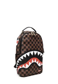 Mochila a cuadros marrón con diseño de boca de tiburón blanca y roja, con una base negra y cremalleras doradas. Material texturizado con detalles.