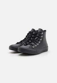 Baskets montantes noires avec une finition en cuir lisse, bouts arrondis, œillets en métal et lacets noirs. Semelle en caoutchouc texturé pour une meilleure adhérence.