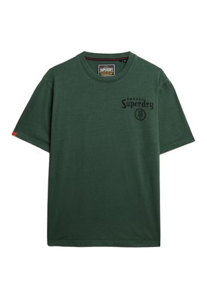 Grøn bomulds t-shirt med korte ærmer, rund hals, logo-tryk foran og et rødt mærke på venstre ærme. Glat tekstur.