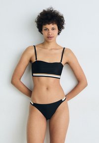 Set di bikini nero con top bandeau caratterizzato da spalline sottili e una fascia multicolore a righe. La parte inferiore è a vita bassa con una striscia simile.