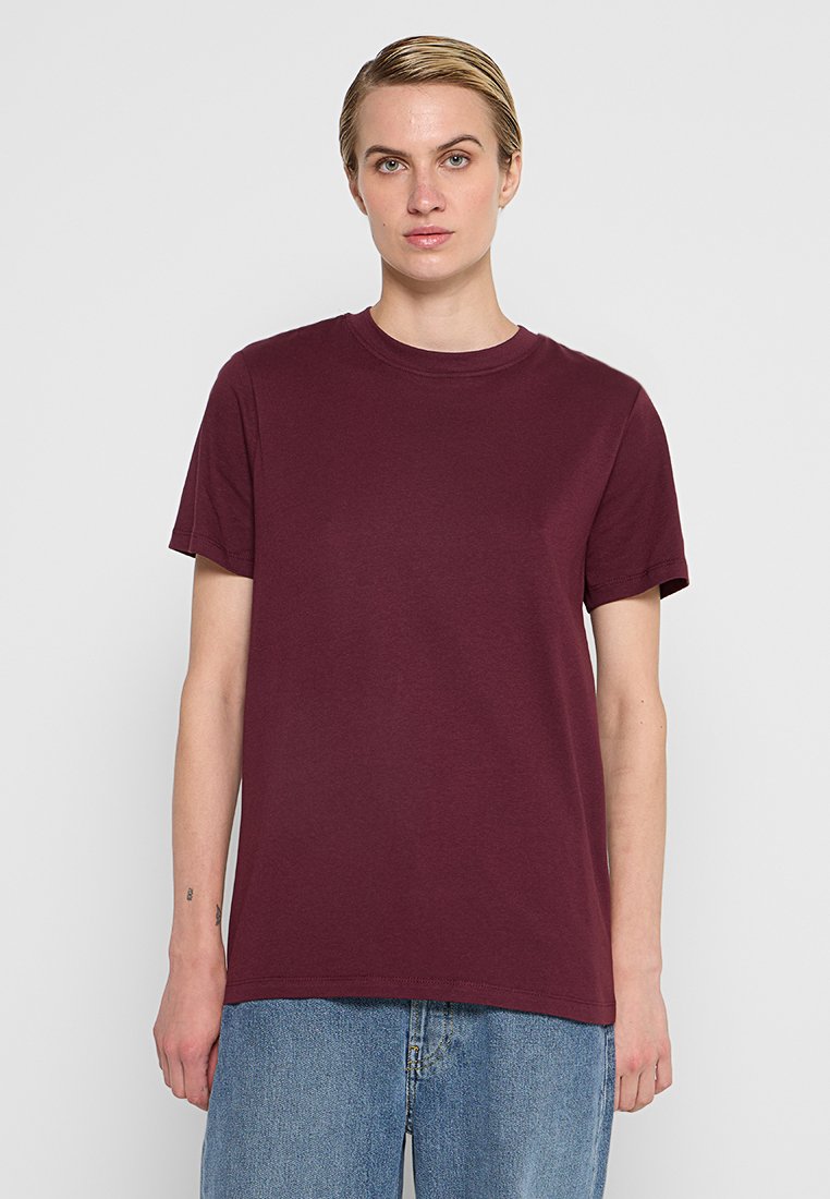 Bordeaux-kleurige katoenen t-shirt met een ronde hals, korte mouwen en een relaxte pasvorm, gecombineerd met lichtblauwe denim jeans.