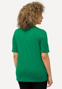 Camiseta verde de manga corta con cuello redondo, hecha de una tela suave. La parte posterior presenta un diseño simple sin patrones o adornos adicionales.