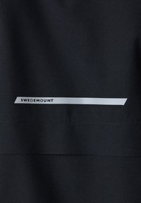 Black fabric with a smooth texture features a white rectangular stripe and text reading "SWEDEMOUNT." Minimalistic design, no visible patterns.